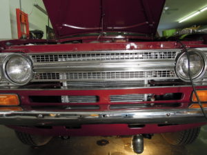 A red truck with its hood open and the front grill.