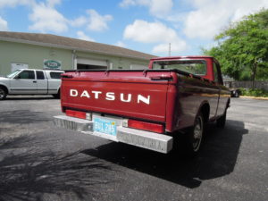 A red truck parked in the parking lot of a business.