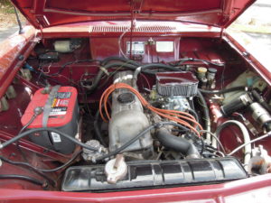 A car engine with the hood open and battery in it.