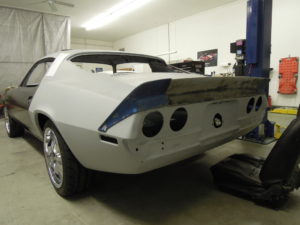 A white car is in the garage with its rear end exposed.