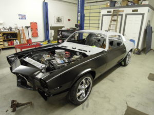 A black car is in the garage with its hood up.