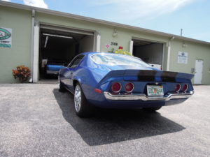 A blue car parked in front of two garage doors.