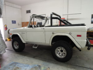 A white bronco truck is parked in the garage.