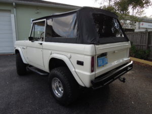 A white bronco is parked in the driveway.