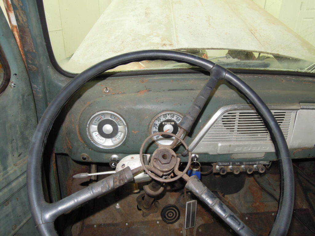 A steering wheel and dashboard of an old truck.