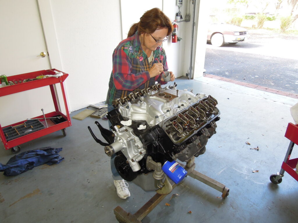 A woman working on an engine in a garage.