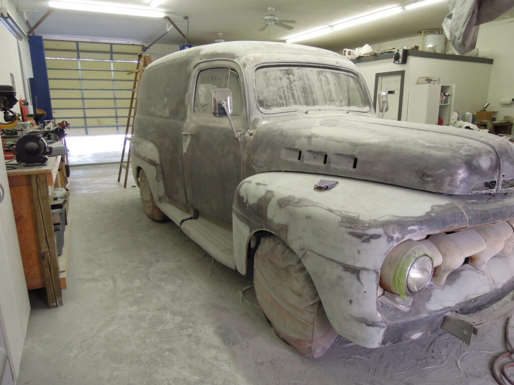 A man standing next to an old truck in a garage.